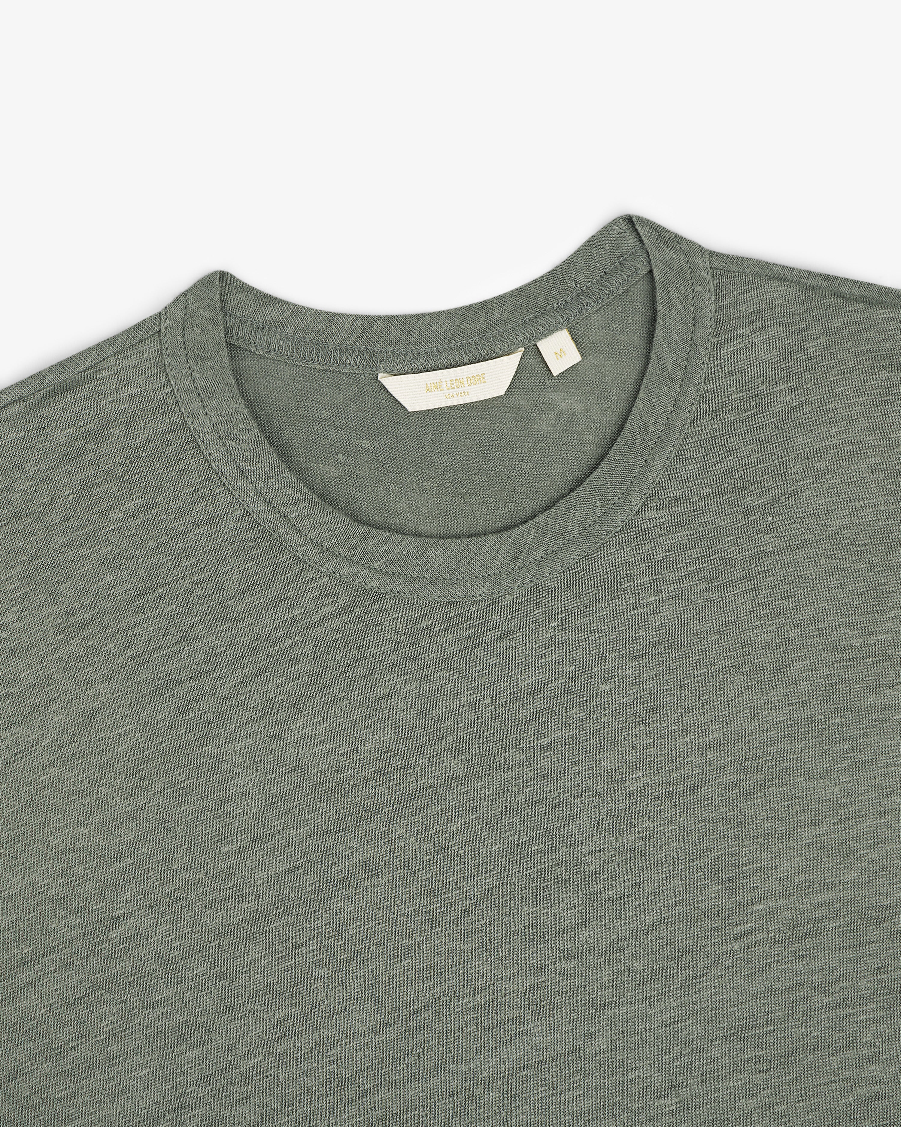 Linen Tee in grayish-green, crew neck style, laid flat to display the collar and inner label.