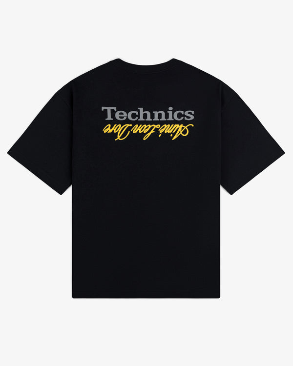 ALD / Technics Logo Tee: Black tee with upside-down gray Technics and yellow Slum Town Hero cursive on the back.