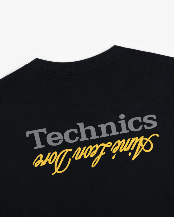 ALD / Technics Logo Tee: Black tee with gray Technics logo and yellow "with love" script, both upside down.