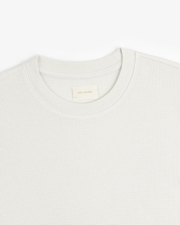 Close-up of a textured, light-colored Long-Sleeve Waffle Thermal crew neck with visible neck label on white background.
