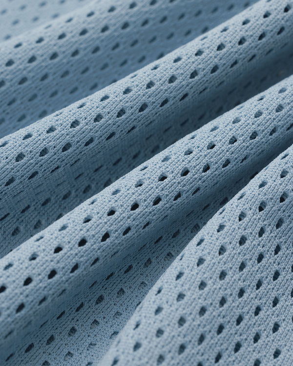 Close-up of Mesh Batting Practice Jersey in light blue, featuring small, evenly spaced holes and gentle folds.
