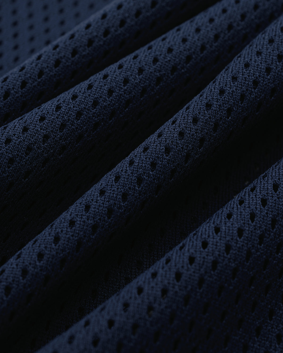 Close-up of the Mesh Batting Practice Jersey’s dark blue perforated fabric with ridges and breathable holes.