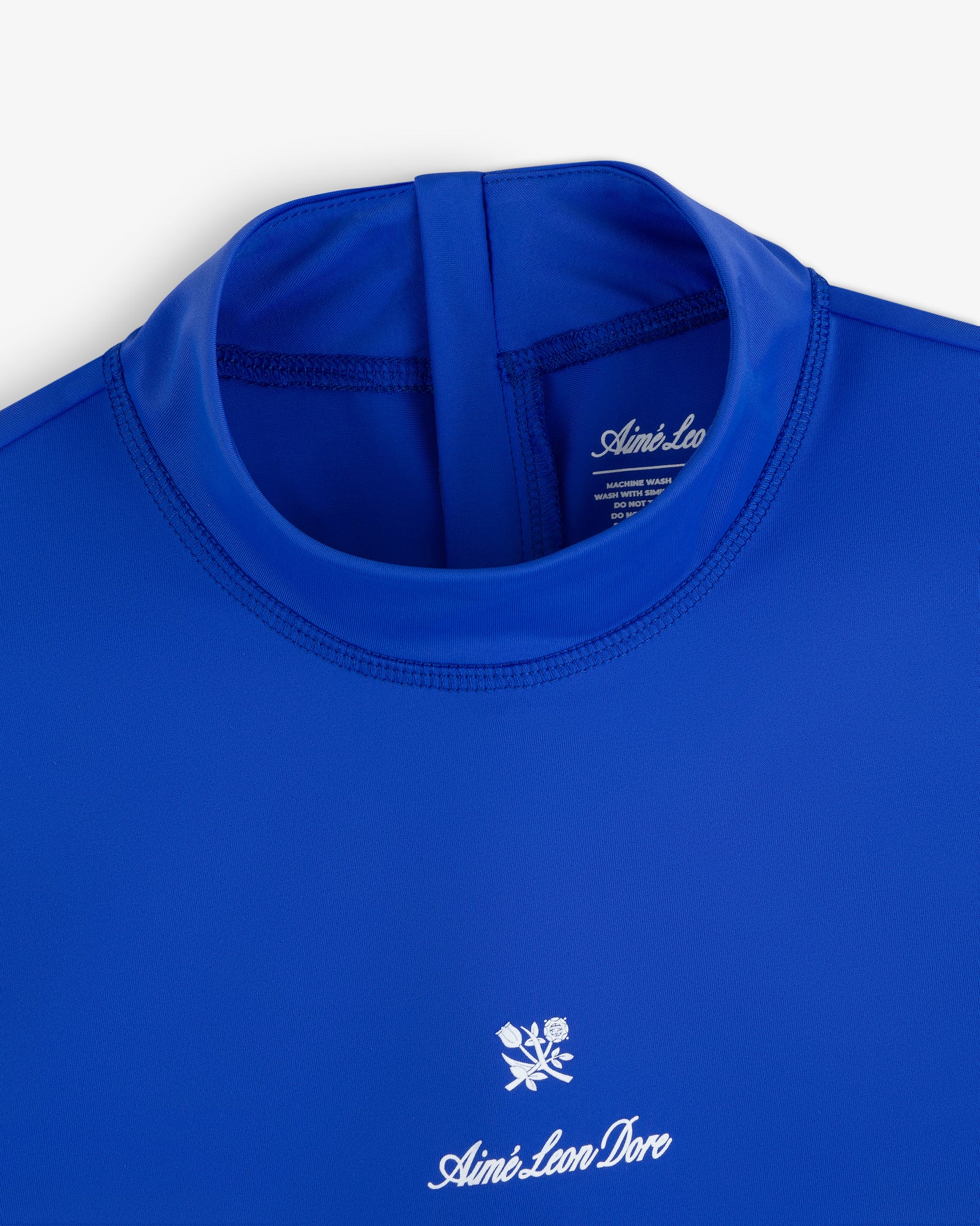 Close-up of the Short Sleeve Crest Rash Guard in royal blue with “Aimé Leon Dore” logo and white rose chest emblem.