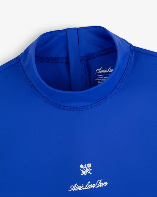 Close-up of the Short Sleeve Crest Rash Guard in royal blue with “Aimé Leon Dore” logo and white rose chest emblem.