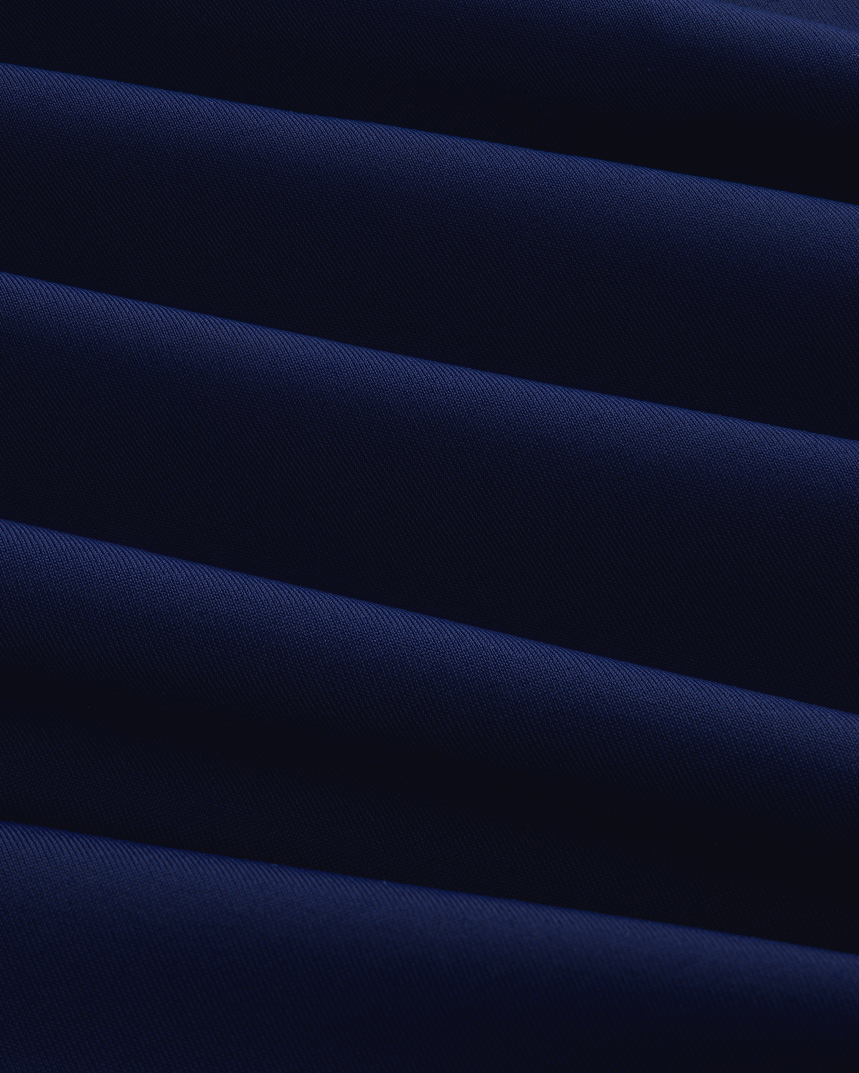 Close-up of Short Sleeve Crest Rash Guard in dark blue with diagonal folds creating light and shadow patterns.