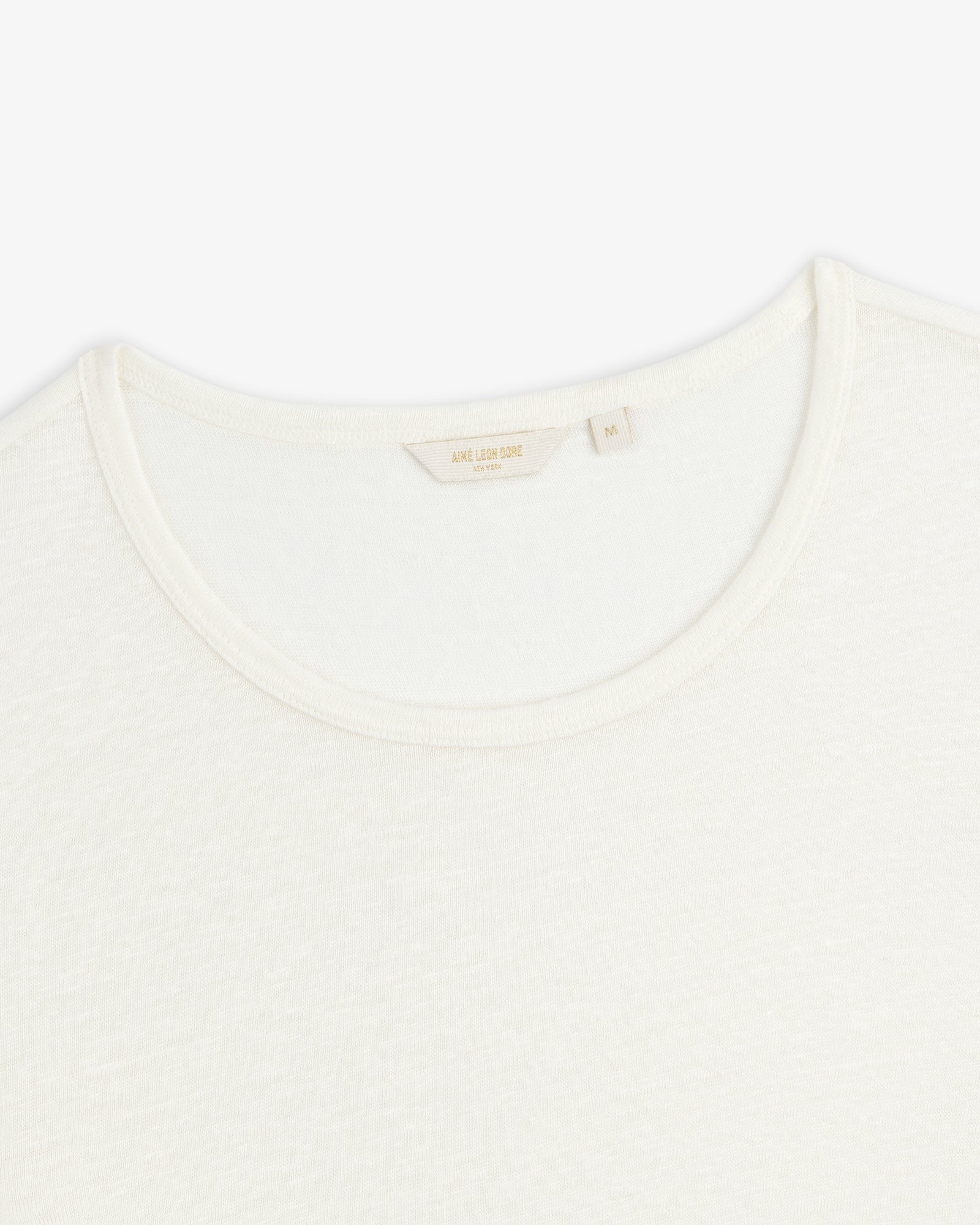 Close-up of the neckline of a plain white Linen Tee crew neck on a white background.