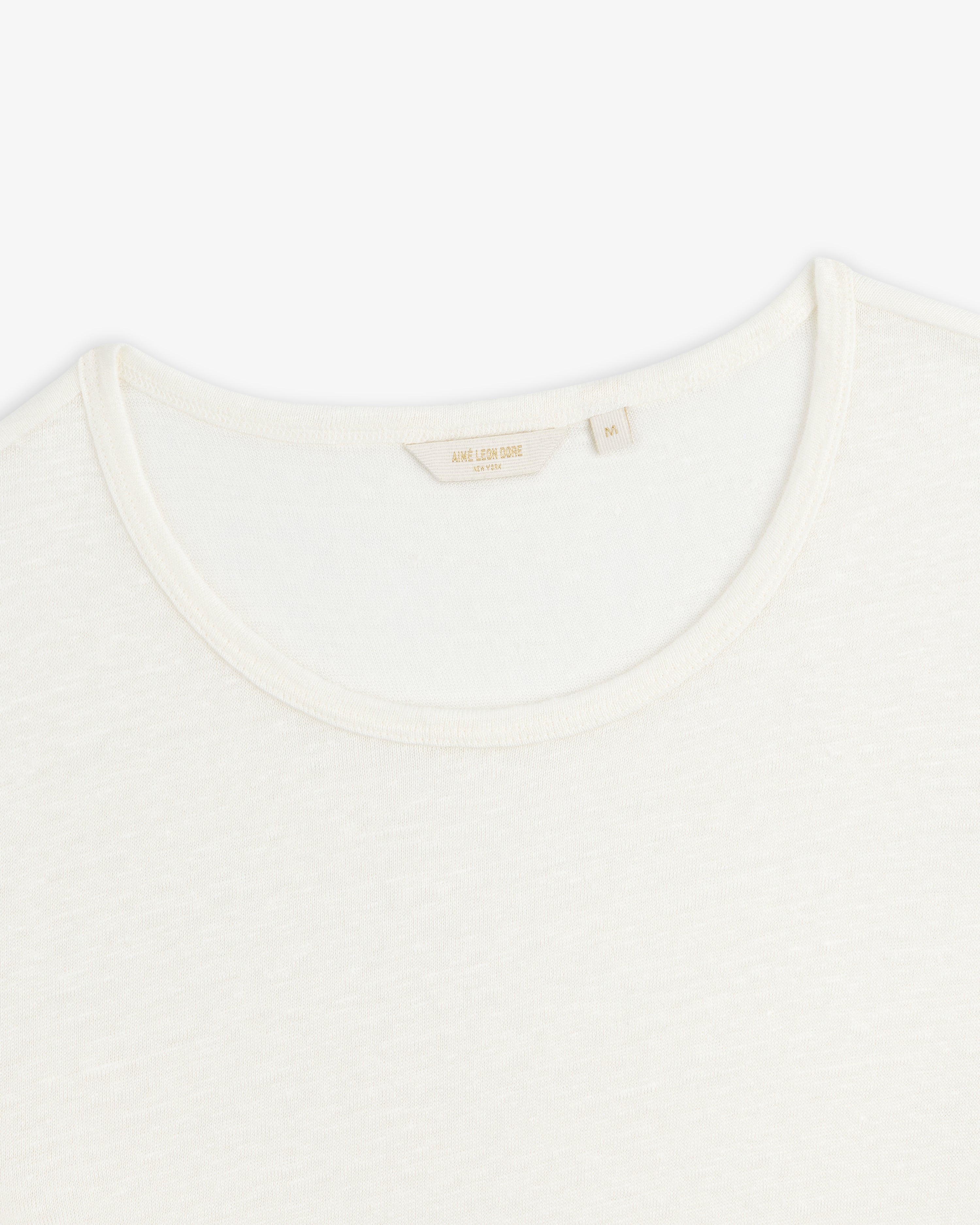Close-up of the neckline of a plain white Linen Tee crew neck on a white background.