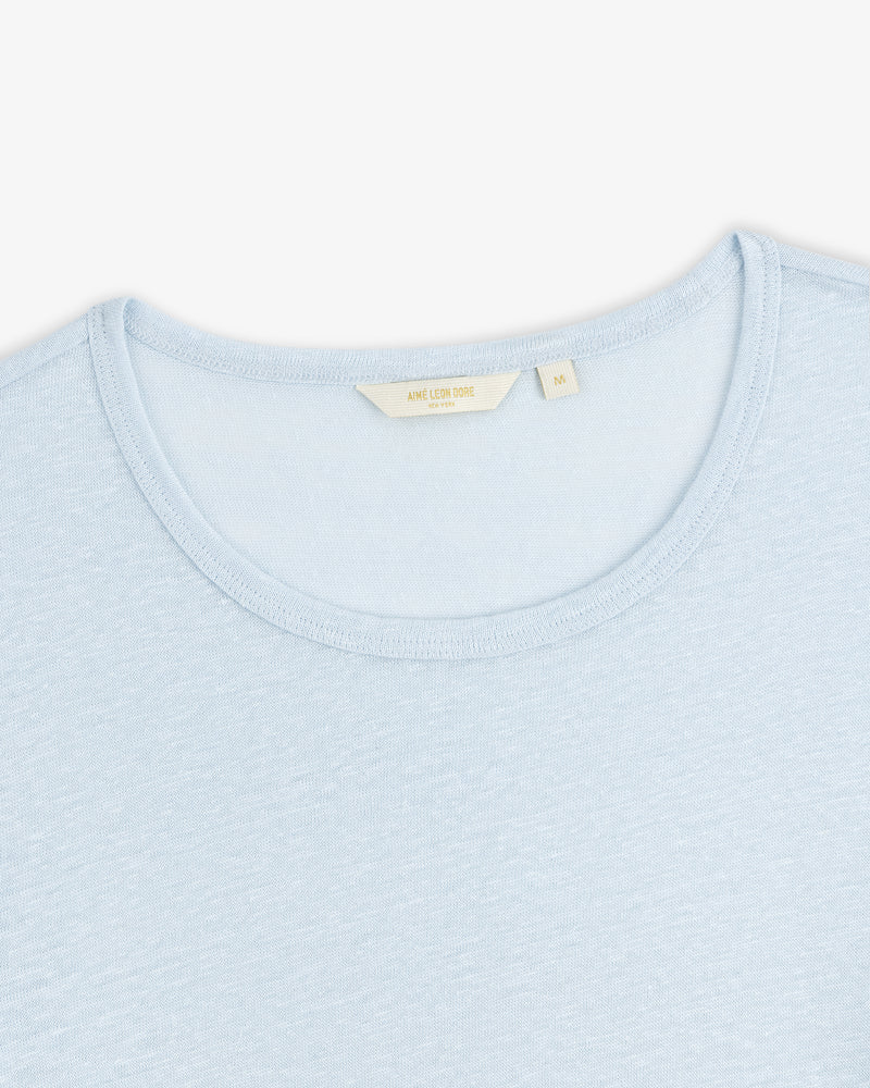 Linen Tee in light blue with a cream-colored label inside the collar, shown on a white background.