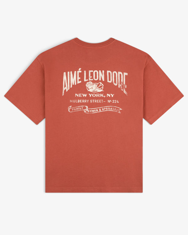 Rust Neighborhood Pocket Tee with vintage white Aimé Leon Dore graphic and New York address on the back.