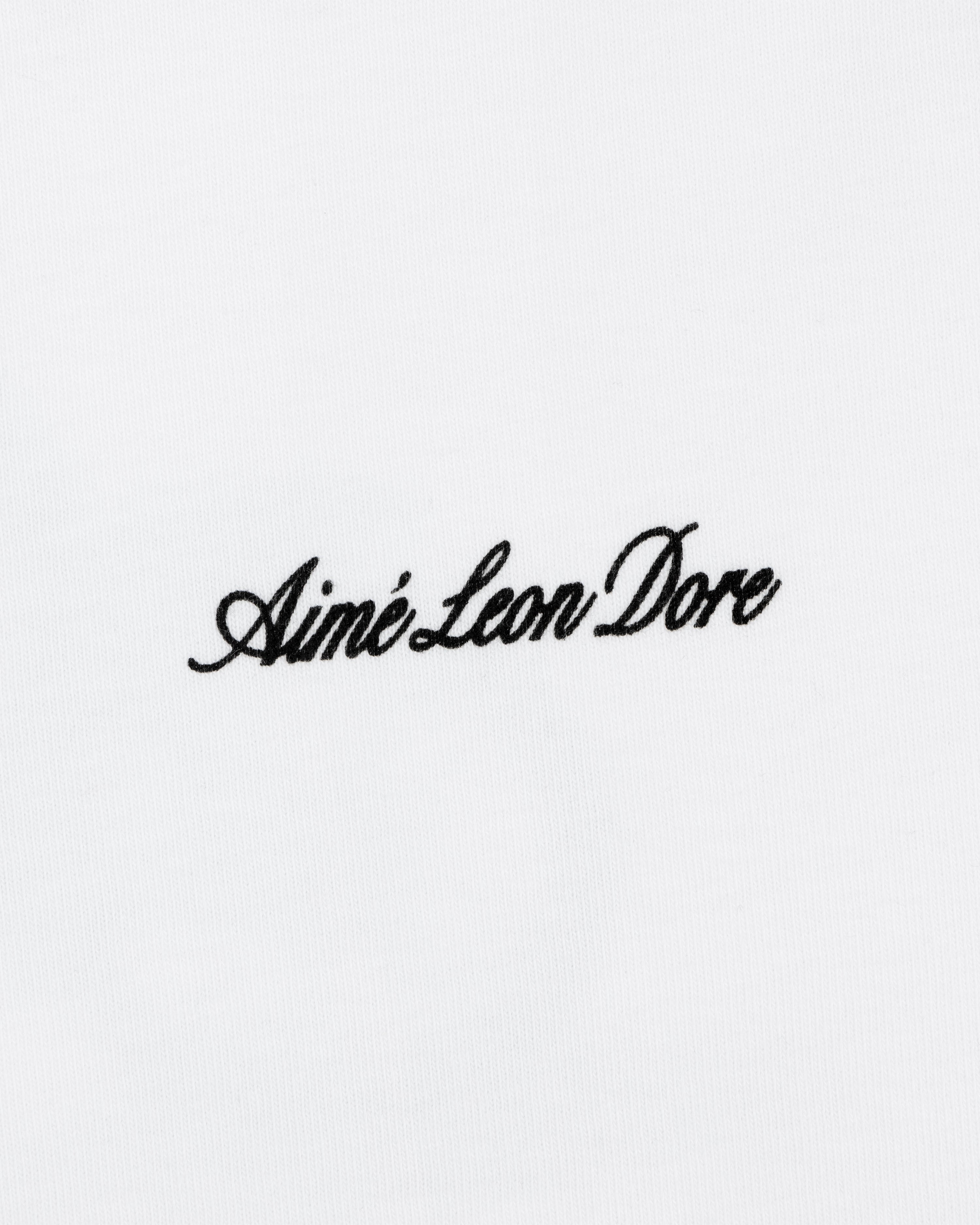 Black script "Aimé Leon Dore" embroidered on a plain white Super Cub Tee.