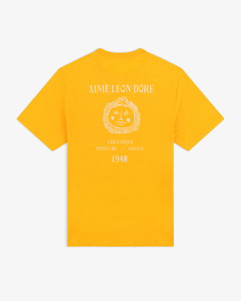 Back of a yellow Artiste Pocket Tee with a sun face graphic and white "Aime Leon Dore" and "1948" text.