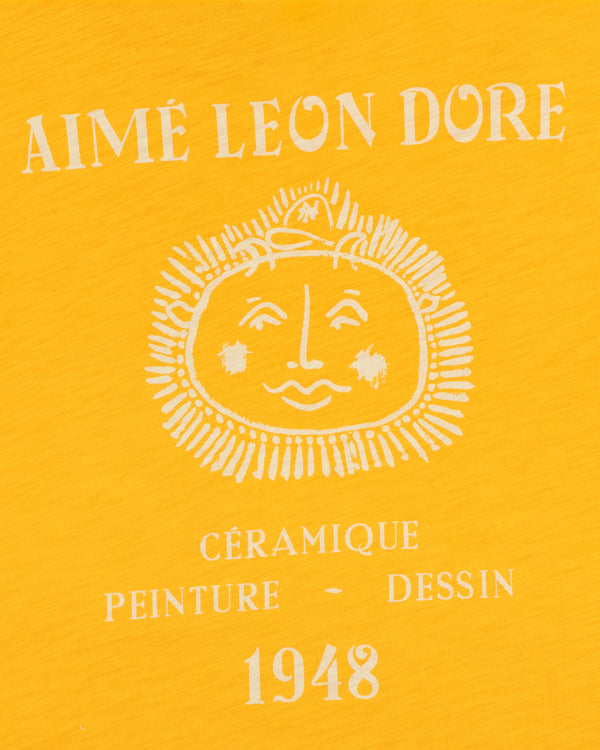 Yellow background, white Aimé Leon Dore text, sun face, Céramique Peinture Dessin 1948 on Artiste Pocket Tee.