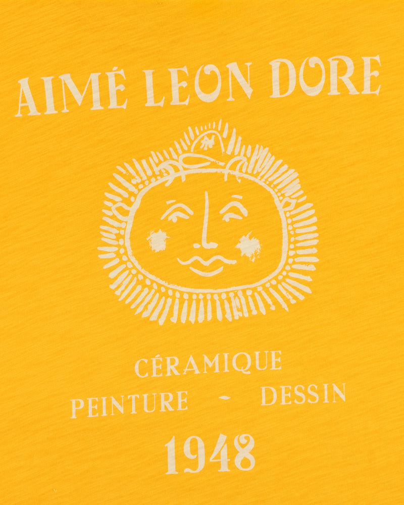 Yellow background, white Aimé Leon Dore text, sun face, Céramique Peinture Dessin 1948 on Artiste Pocket Tee.