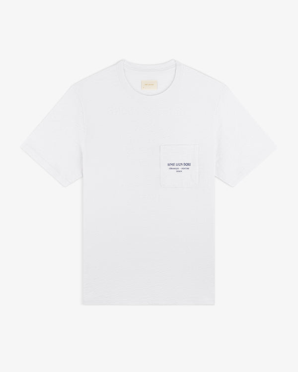 Artiste Pocket Tee: White short-sleeve T-shirt with a chest pocket and small printed text on the pocket.