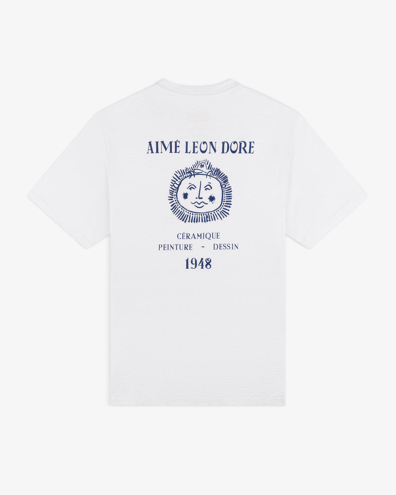 Artiste Pocket Tee: White shirt with blue AIMÉ LEON DORE text, sun face graphic, French words & 1948 on back.
