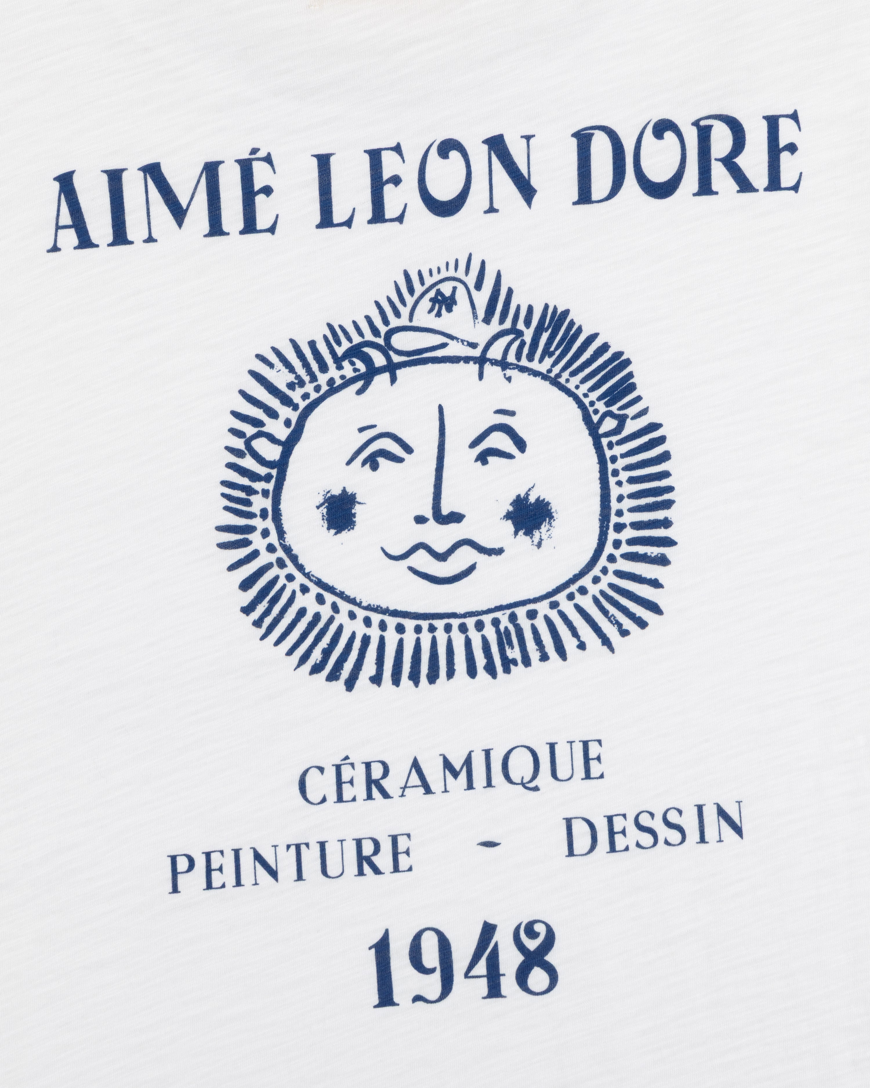 White Artiste Pocket Tee with AIMÉ LEON DORE above a sun face and CÉRAMIQUE PEINTURE DESSIN 1948 below.