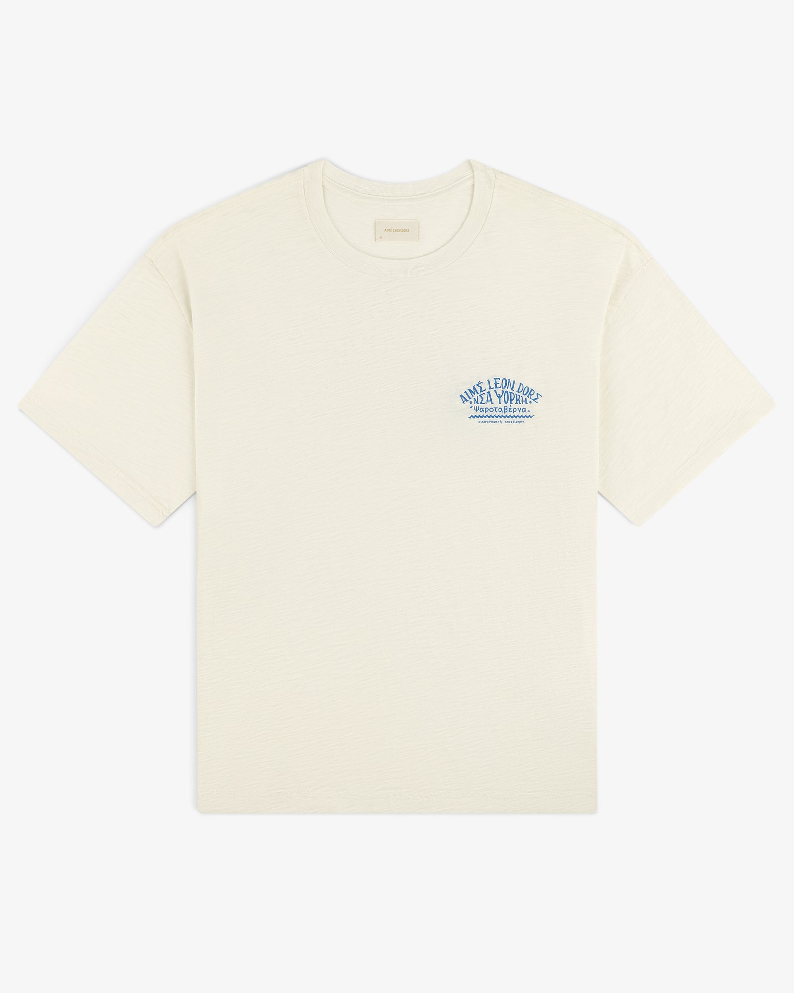 Taverna Tee: Cream short-sleeve shirt with small blue text and graphic on left chest.