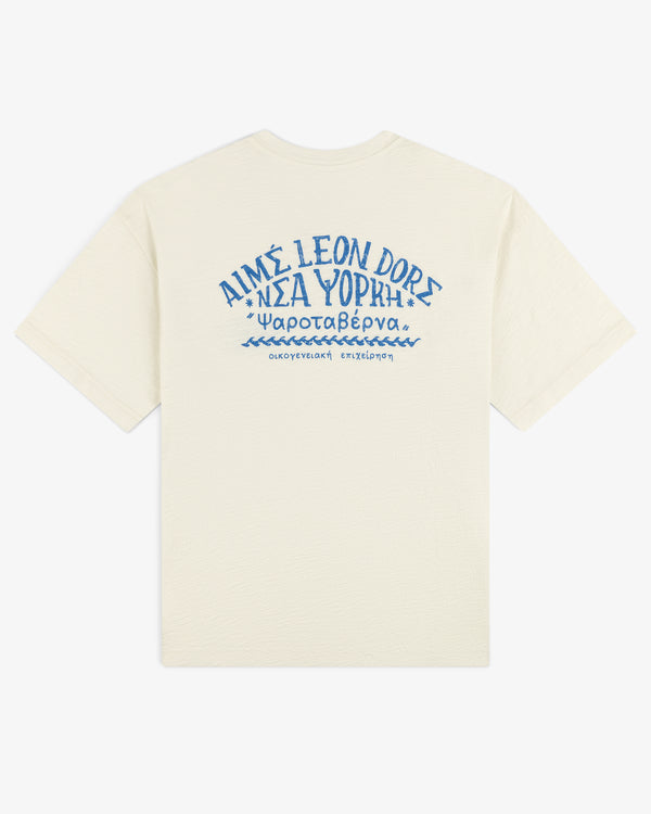 Off-white Taverna Tee with blue Greek text and AIMÉ LEON DORE printed on the upper back.