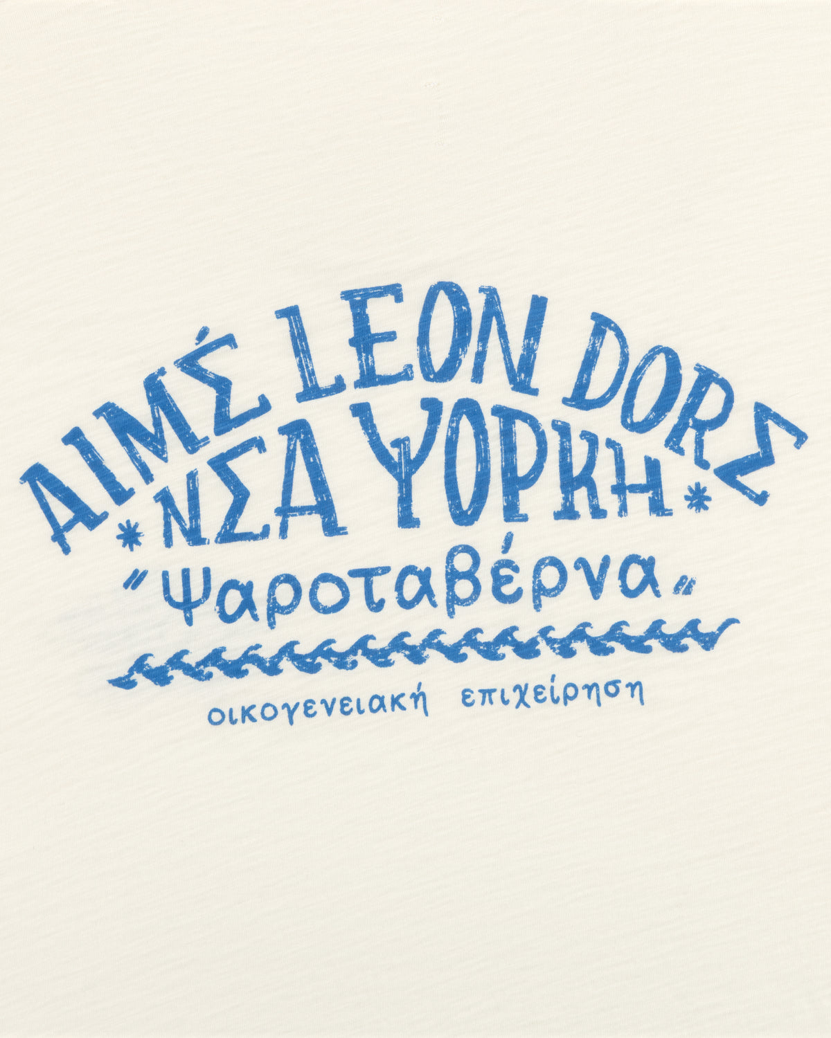 Blue Greek-style text on a white tee reads Aimé Leon Dore Νέα Υόρκη Ψαροταβέρνα οικογενειακή επιχείρηση.