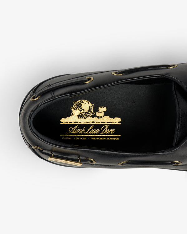 Top view of the Pápia Boat Shoe in black leather with gold Aimé Leon Dore branding and globe design on the insole.
