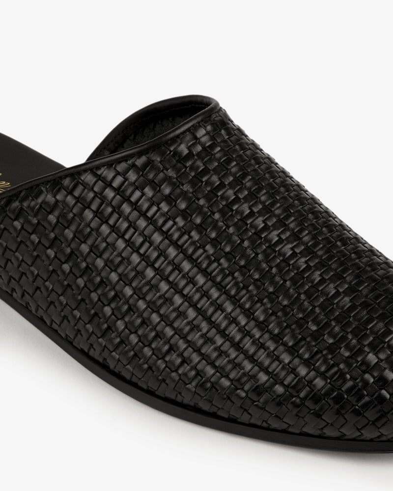 Close-up of the Leather Raffia Mule, a black woven leather slip-on, against a white background.