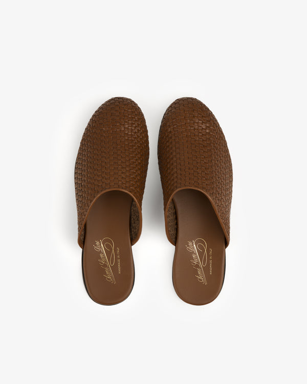 Top view of Leather Raffia Mule, a pair of brown woven slip-on shoes with closed toes, on a white background.