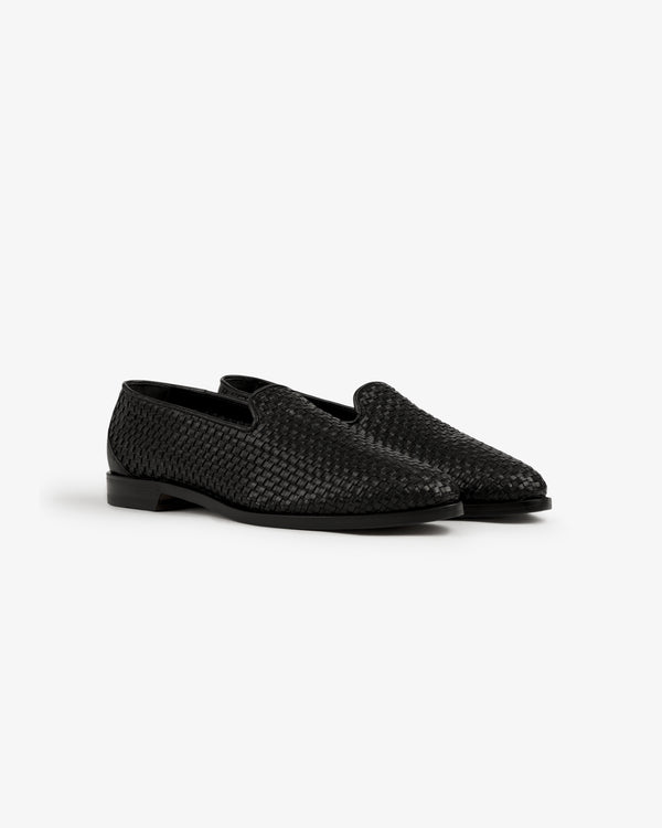 The Leather Raffia Loafer is a pair of black woven leather low-heel loafers shown on a white background.