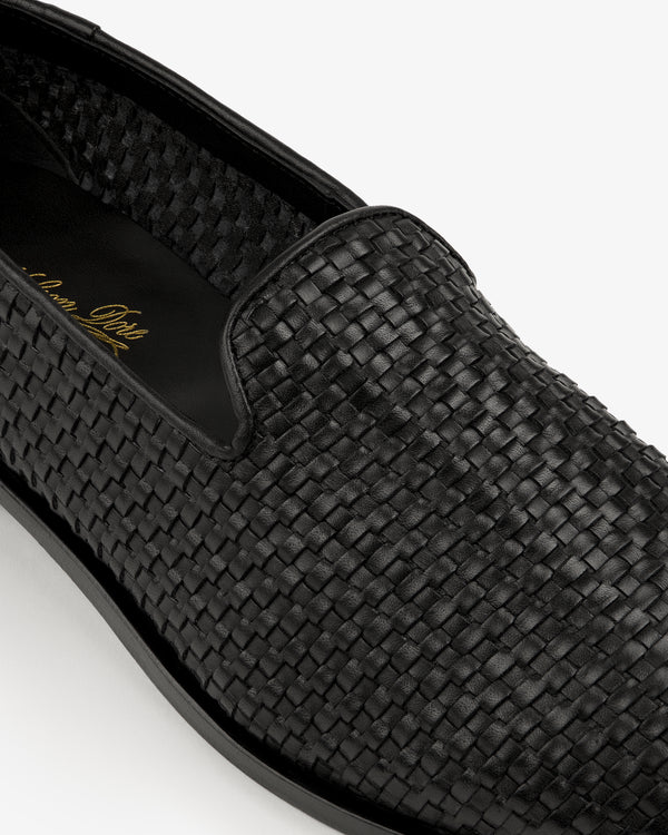 Close-up of a Leather Raffia Loafer in black with woven leather, smooth sole, and gold writing on the insole.