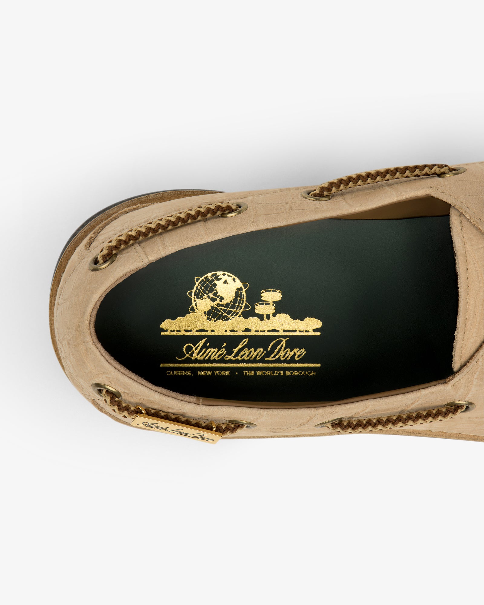 Top view of Pápia Boat Shoe in beige with gold Aimé Leon Dore logo and globe graphic on the green insole.