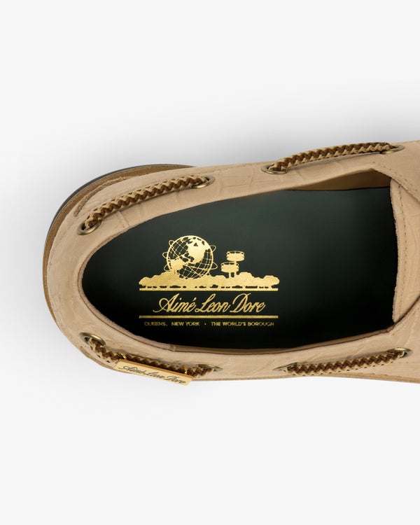 Top view of Pápia Boat Shoe in beige with gold Aimé Leon Dore logo and globe graphic on the green insole.