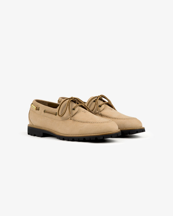 Pápia Boat Shoe: tan leather, black sole, gold tags, visible stitching, on a plain white background.