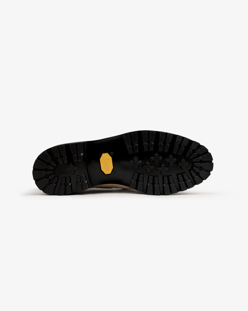 The Pápia Boat Shoe features a black, rugged outsole with deep treads and a yellow hexagonal logo in the center.