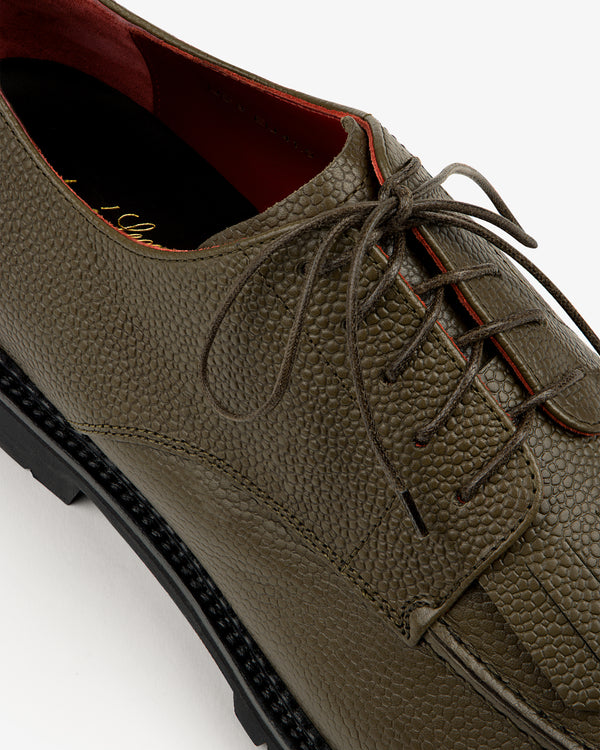 Close-up of Leather Lug Sole Derby in textured olive green leather with black sole and red interior lining.
