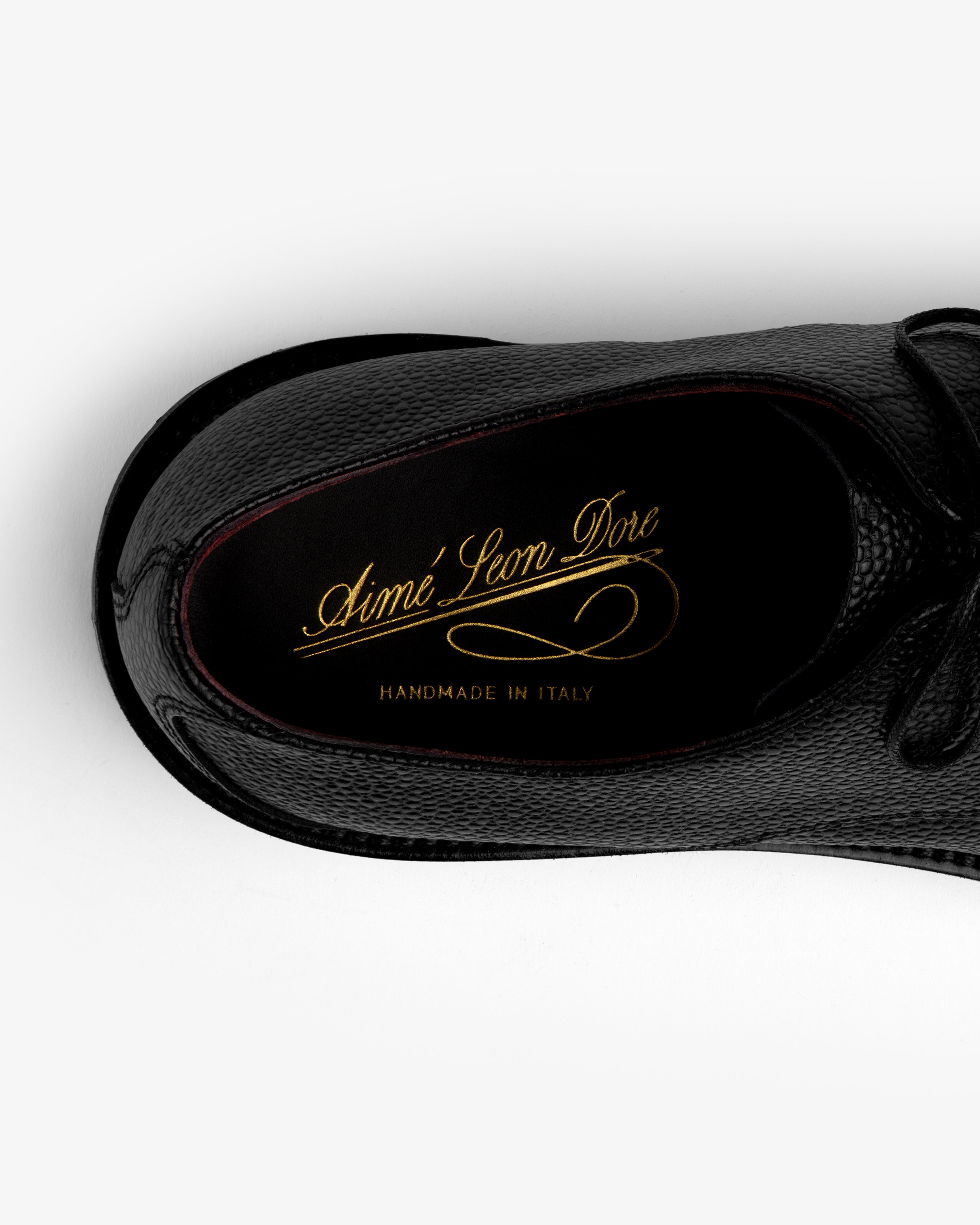 Top-down view of a black Leather Lug Sole Derby shoe with gold branding printed on the insole.