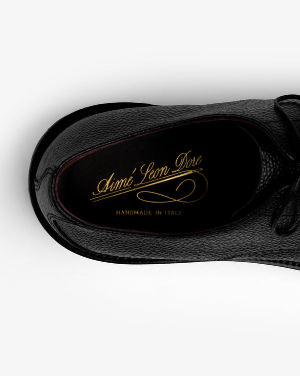 Top-down view of a black Leather Lug Sole Derby shoe with gold branding printed on the insole.