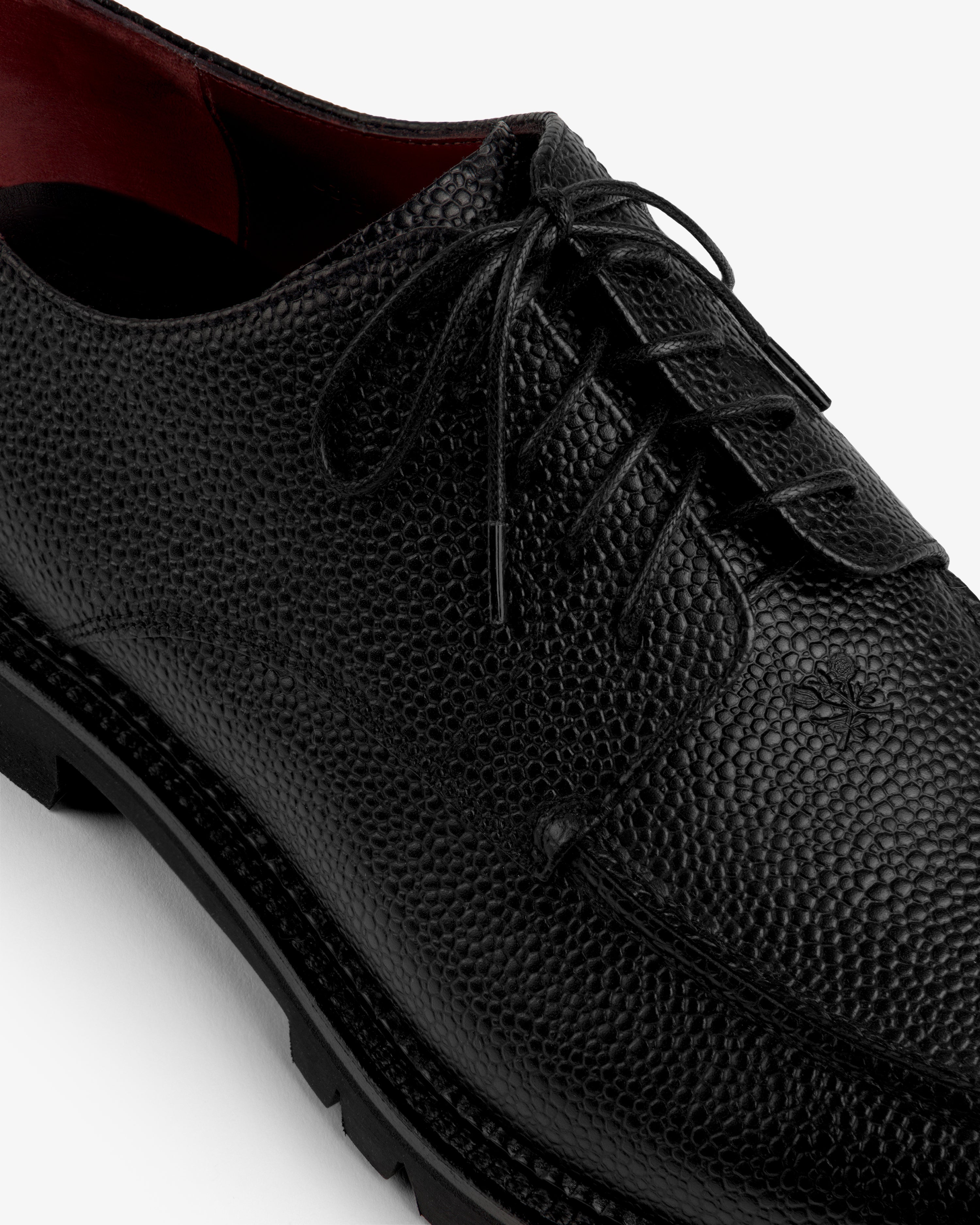 Leather Lug Sole Derby in black lace-up style with a textured finish, thick lug sole, and red interior.