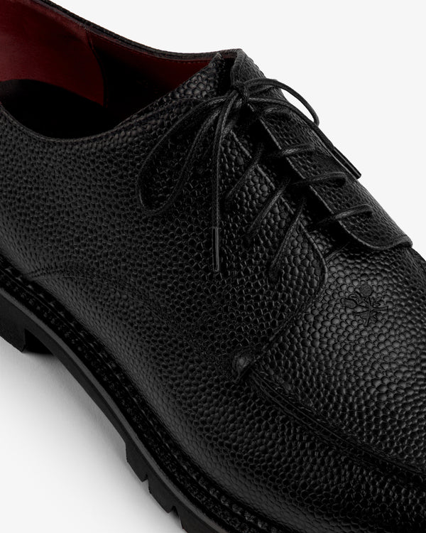 Leather Lug Sole Derby in black lace-up style with a textured finish, thick lug sole, and red interior.