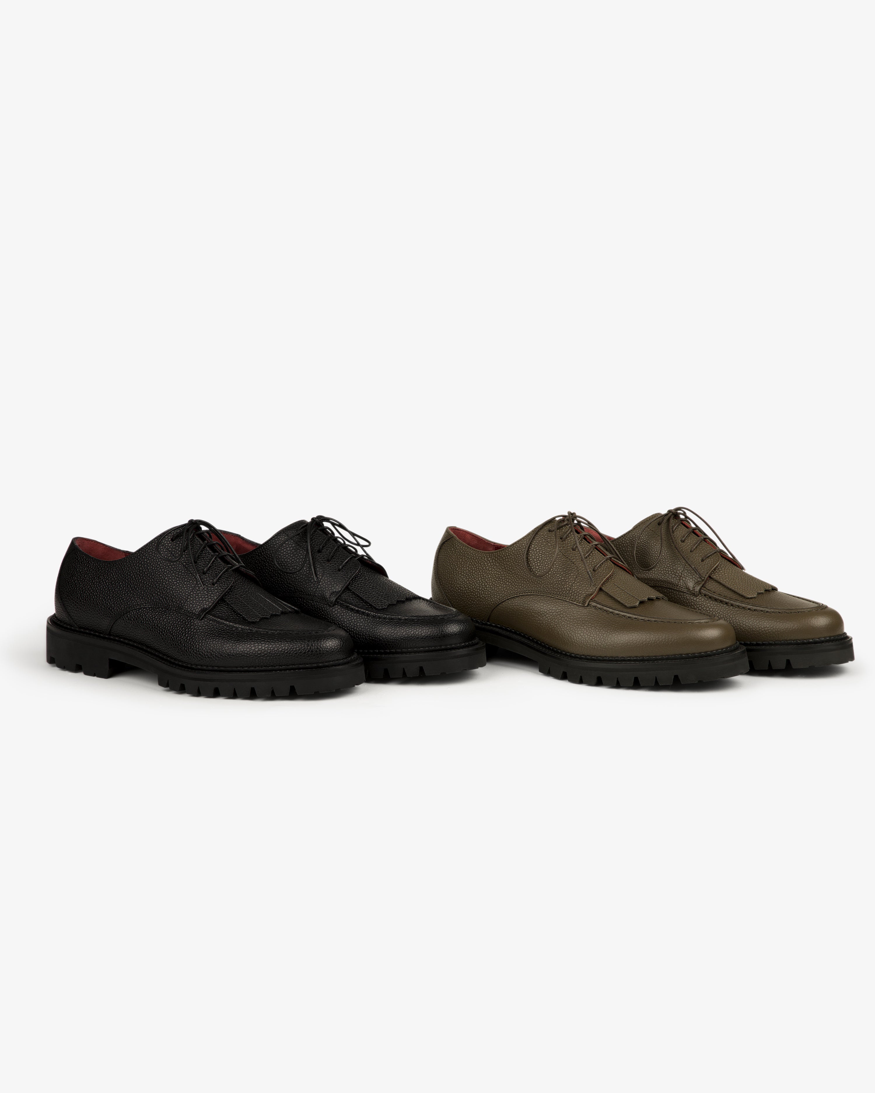 Two Leather Lug Sole Derby shoes, one black and one olive green, displayed side by side on a white background.