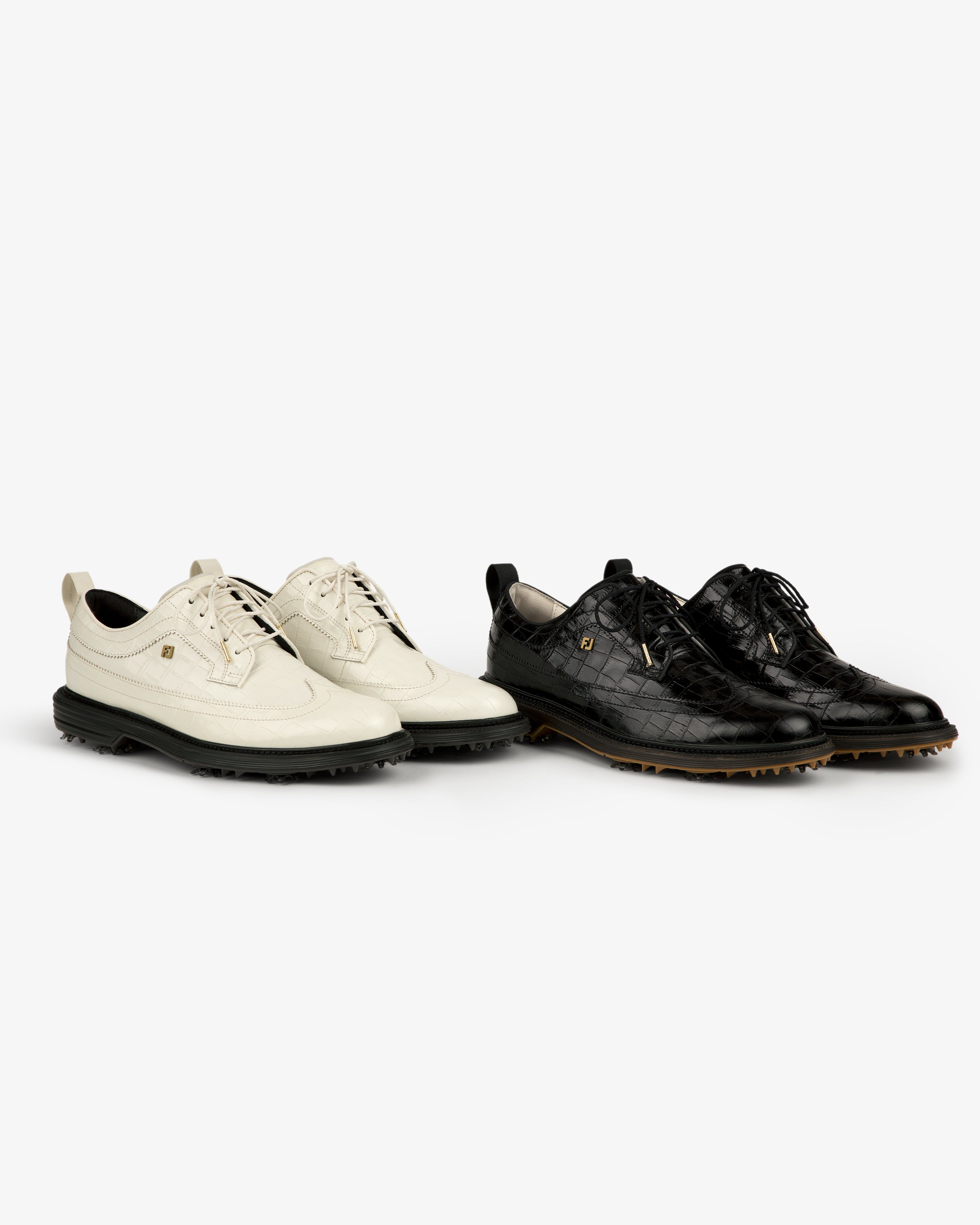 Two ALD / Footjoy Croc-Embossed Premiere Series Marquis shoes, one white and one black, side by side on white.