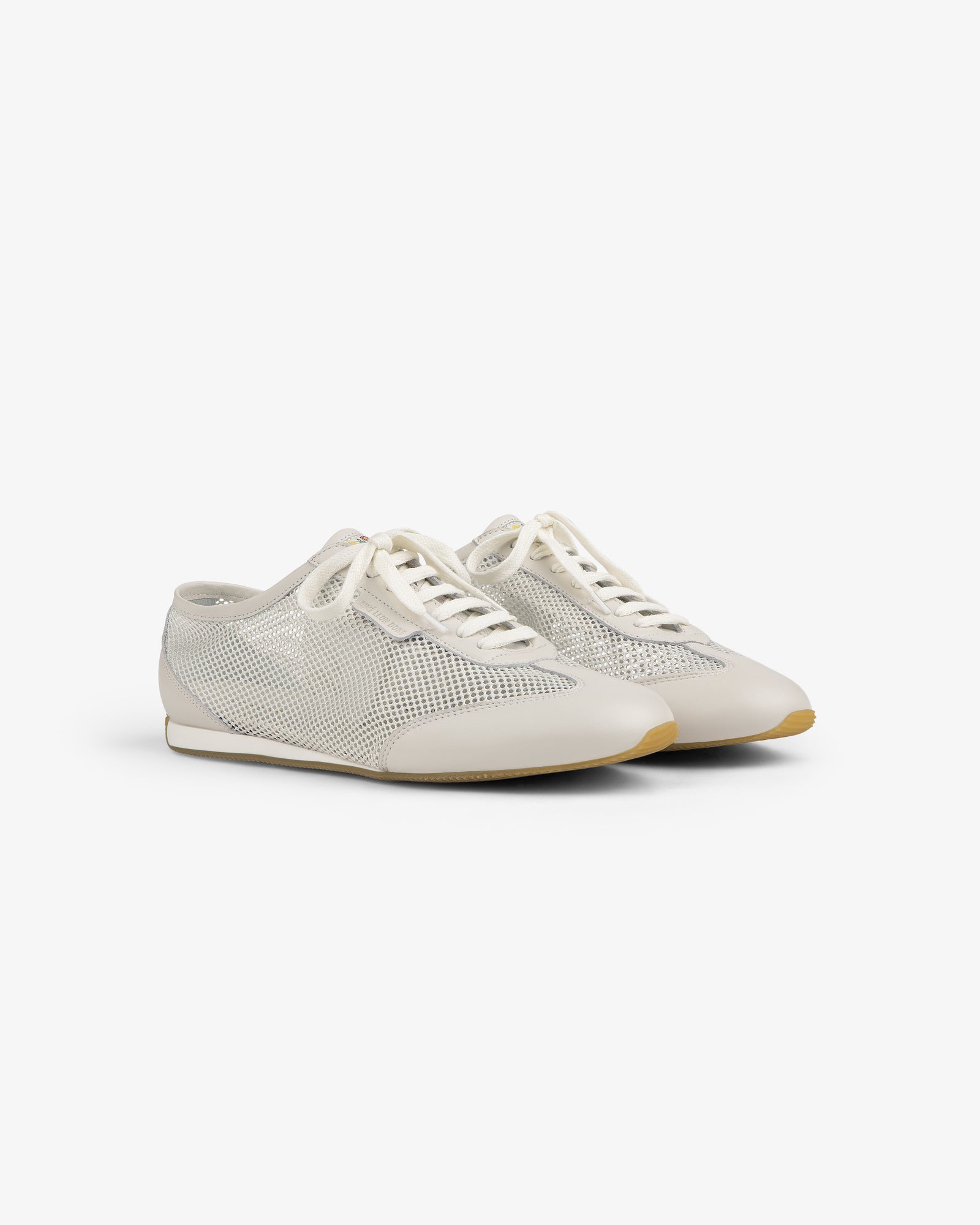 Low Profile Mesh Trainer: white mesh sneakers with lace-up fronts and beige soles, shown on a plain white background.