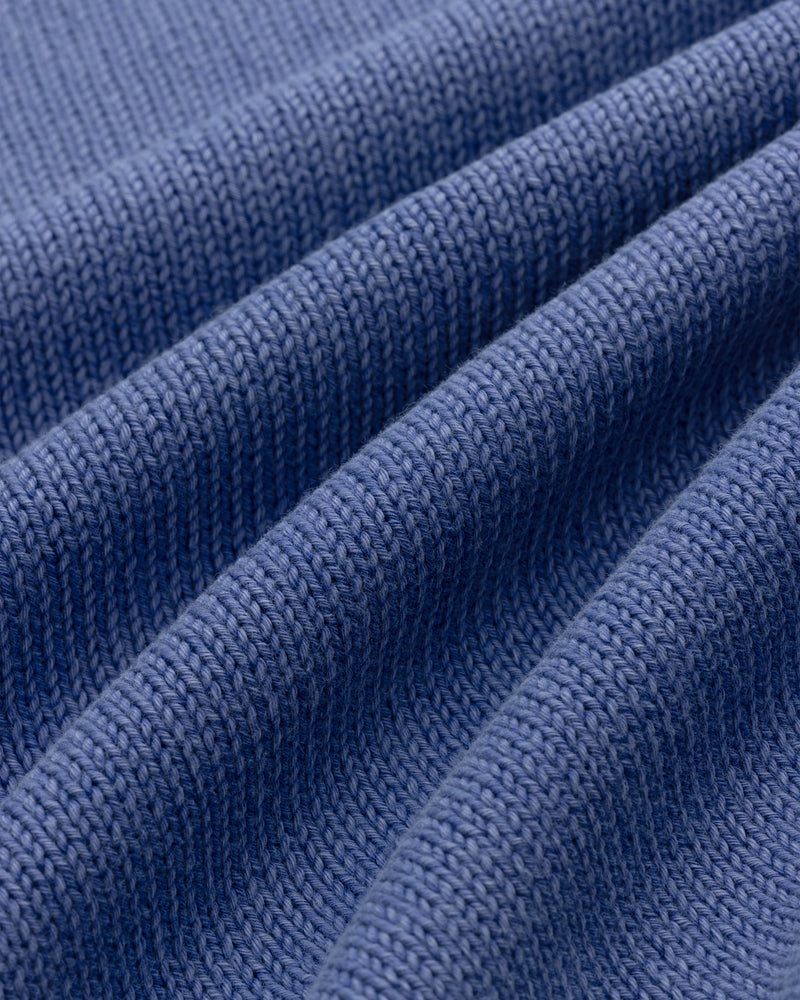 Close-up of Washed Inside Out Sweater’s blue knit fabric, showing visible texture and horizontal folds.
