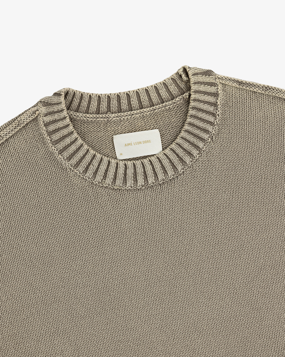 Washed Inside Out Sweater: Beige knit crewneck with ribbed collar and a white label at the neckline.