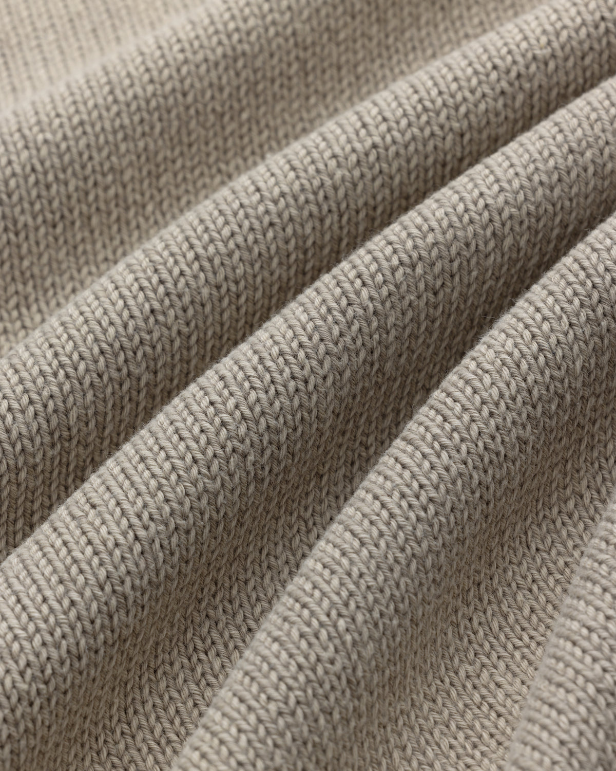 Close-up of Washed Inside Out Sweater in beige, showing textured knit stitches and gentle folds.