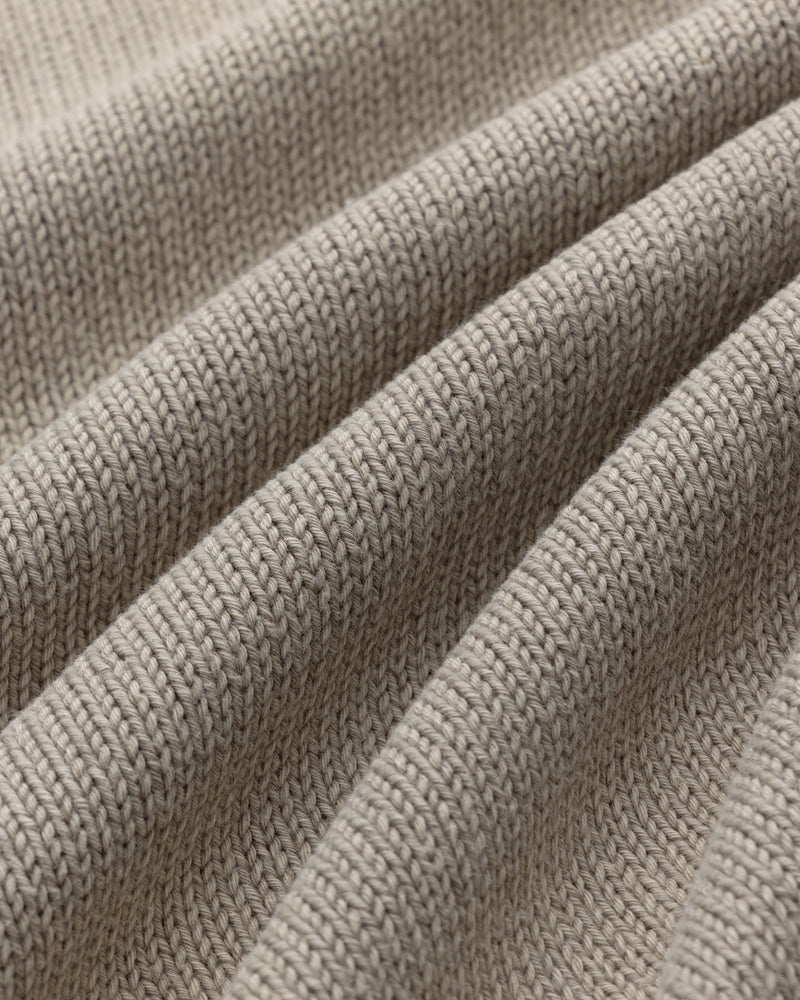 Close-up of Washed Inside Out Sweater in beige, showing textured knit stitches and gentle folds.