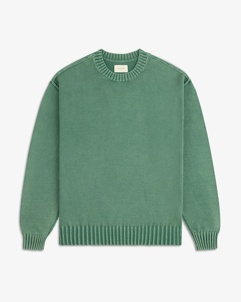The Washed Inside Out Sweater is a plain green, long-sleeve crew-neck with ribbed cuffs, collar, and hem on white background.