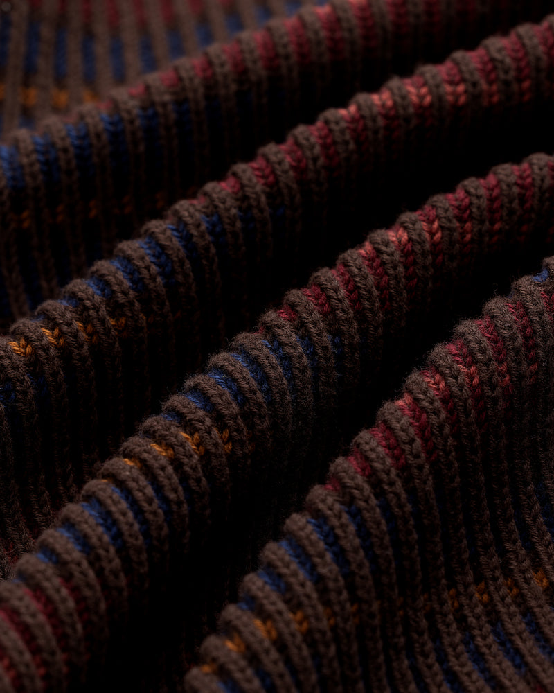 Close-up of Multi Color Knit Track Sweater with brown ribbed fabric and blue, orange, and red striped wavy folds.