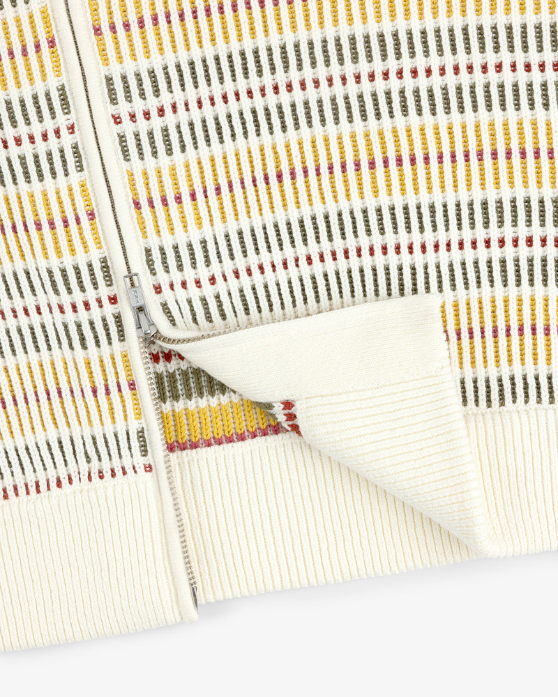 Close-up of the Multi Color Knit Track Sweater featuring a cream zip-up style with vertical yellow, olive, and red stripes.