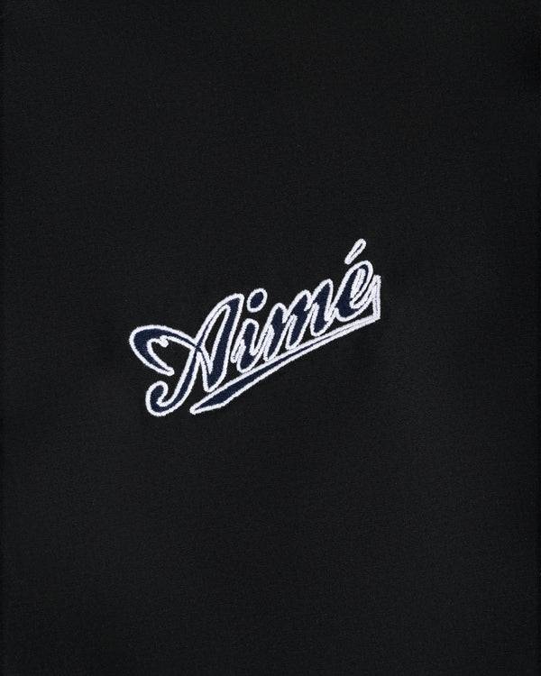 White Aimé script embroidered on black fabric of the Reversible Knit Bomber Jacket.