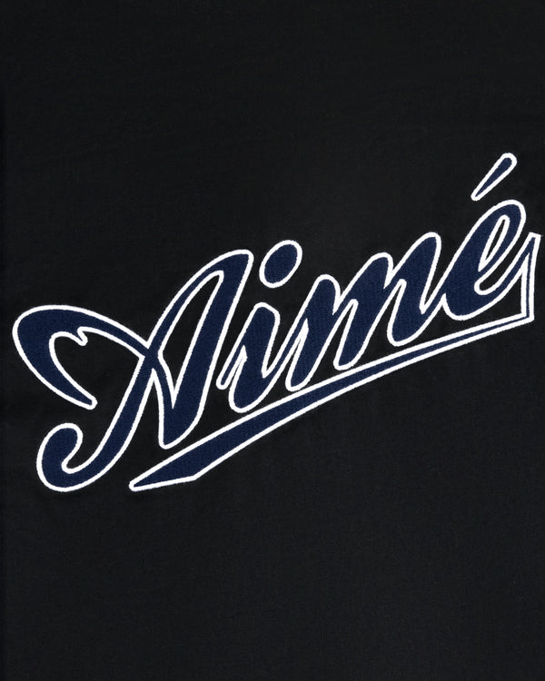 Aimé in white cursive with blue outline on black, featured on the Reversible Knit Bomber Jacket.