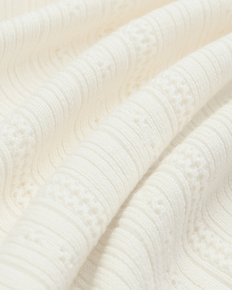 Close-up of textured Merino Wool Eyelet Tee featuring off-white raised, wavy knit patterns and intricate details.
